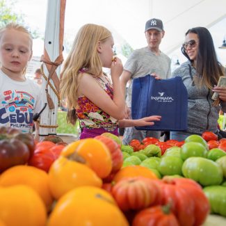family buying vegetables at farmers market